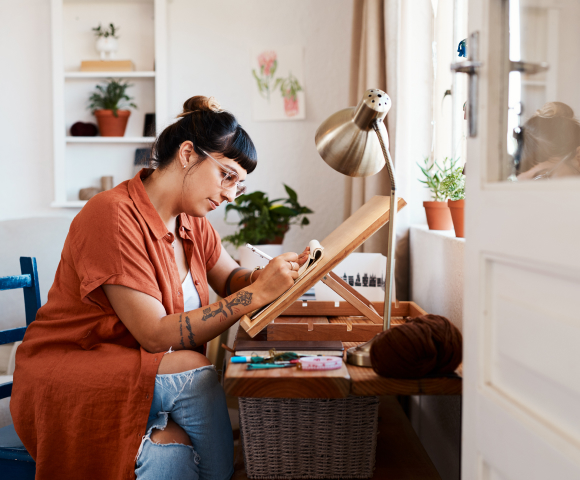 Mujer trabajando concentrada en su mesa junto a la ventana