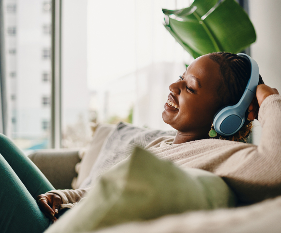 Mujer con auriculares trabajando con su portátil en el sofá